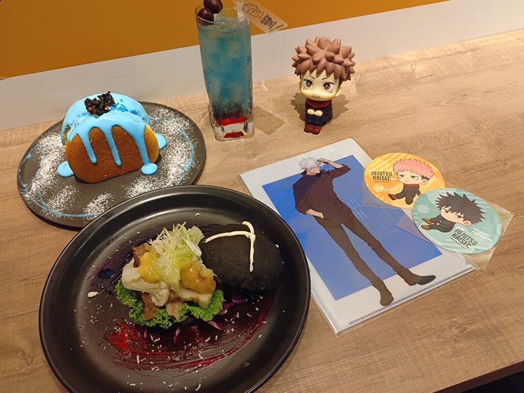 呪術廻戦カフェ2025渋谷事変の五条悟メニュー3種セット。西京『最強』味噌サンド、『無下限呪術』パンケーキ、ザクロ＆ライチドリンクを並べて撮影した写真。最強の術師・五条悟をテーマにしたフード、デザート、ドリンクが一緒に写っている。