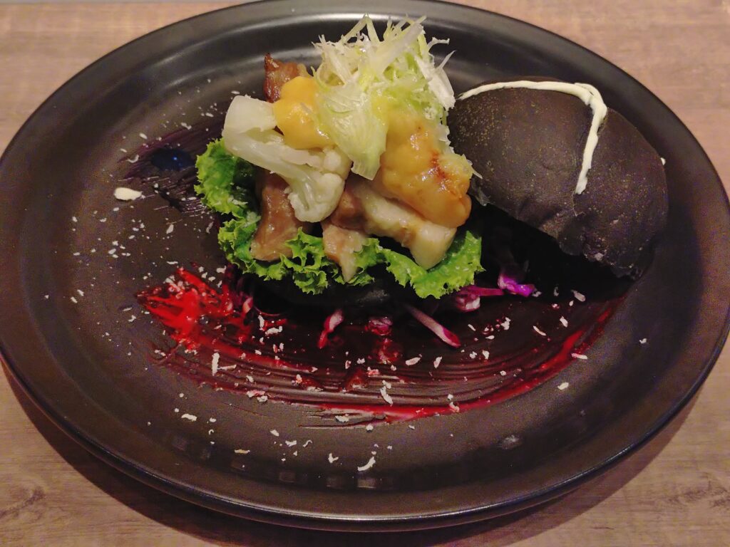 呪術廻戦カフェ2025渋谷事変の五条悟メニュー、西京『最強』味噌サンド。現代最強の術師・五条悟をイメージした西京味噌ソースのポークサンドウィッチで、『蒼』と『赫』を表現したマヨネーズソースが添えられている。