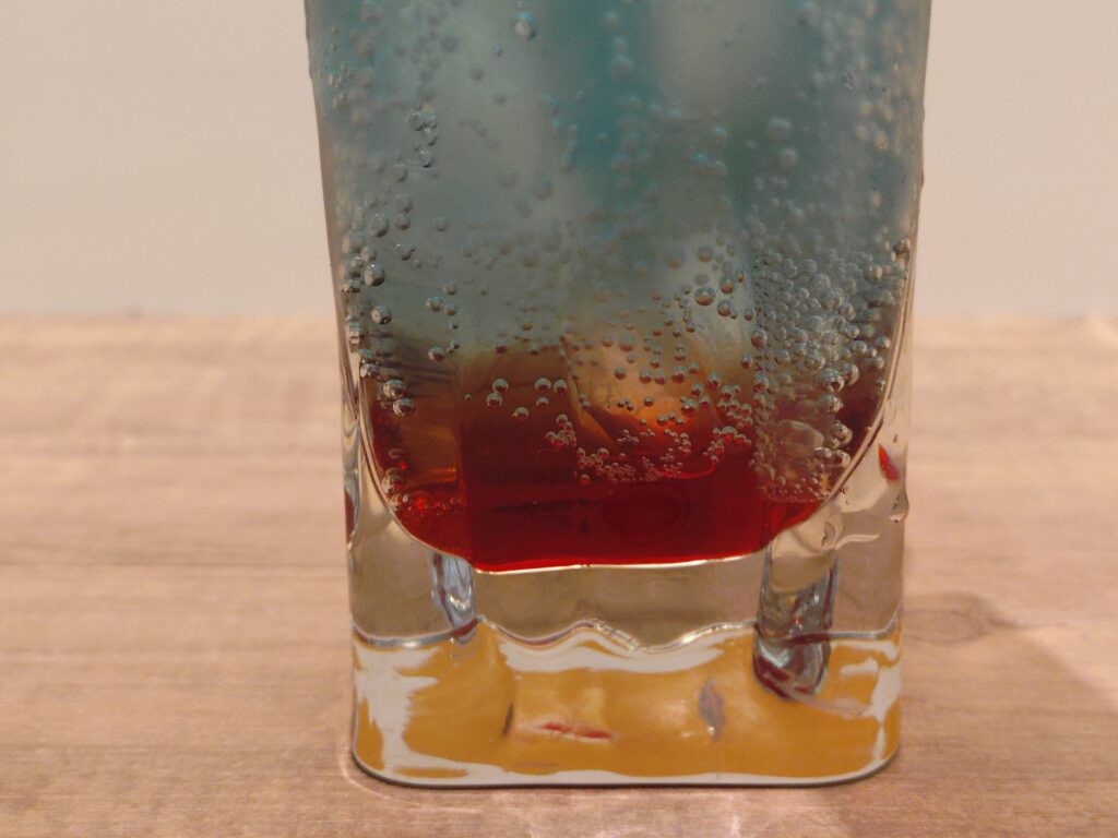 呪術廻戦カフェ2025渋谷事変の五条悟メニュー、ザクロ＆ライチドリンク。五条悟をイメージしたザクロとライチ風味の炭酸ソーダで、透明感ある見た目が特徴。