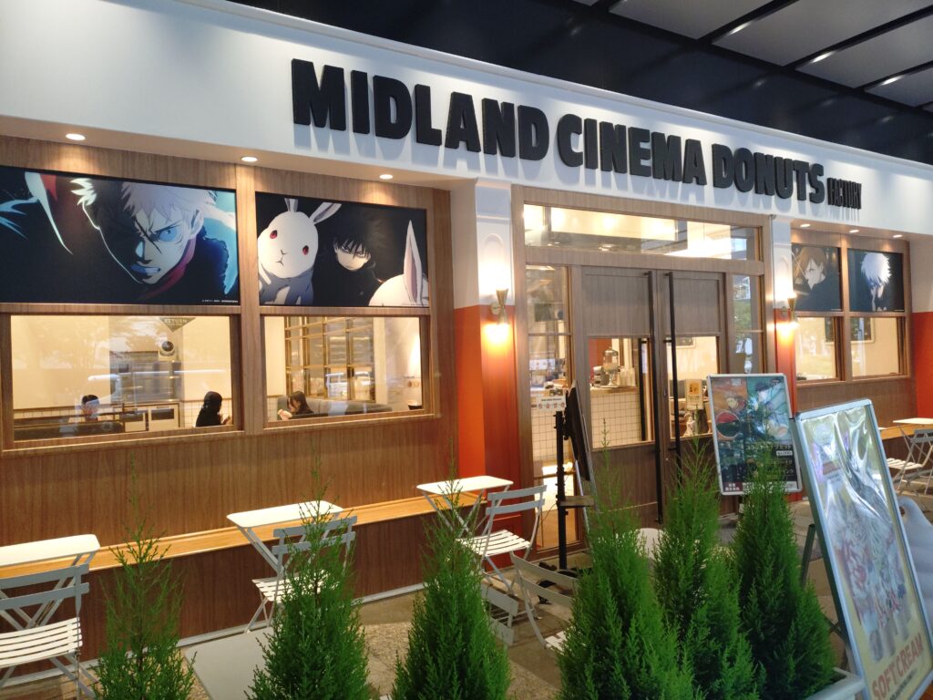 2025年MIDLAND CINEMA DONUTS FACTORYの呪術廻戦コラボ外装。店舗全体が虎杖悠仁・伏黒恵・釘崎野薔薇・五条悟のイラストでラッピングされている。